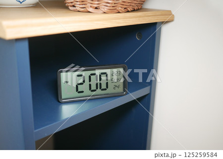 Digital clock displaying time and temperature on a shelf Digital clock displaying time and temperature on a shelf 125259584