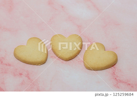 ピンクの大理石模様背景のハート型クッキー 125259684