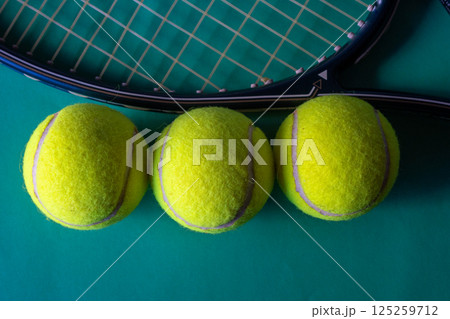 Three tennis balls next to a racket. Top view. Sport concept Three tennis balls next to a racket. Top view. Sport concept 125259712