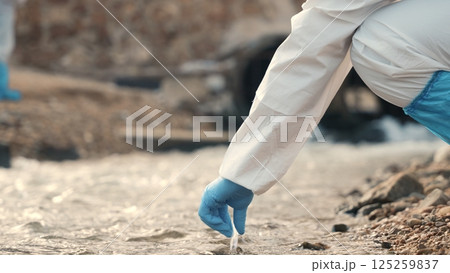 Ecologist sampling water from the river with test tube, Biologist wear protective suit and mask collects sample of waste water from industrial, problem environment, scientist environmentalist Ecologist sampling water from the river with test tube, Biologist wear protective suit and mask collects sample of waste water from industrial, problem environment, scientist environmentalist 125259837