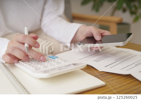 電卓で計算をする女性の手元 電卓で計算をする女性の手元 125260025