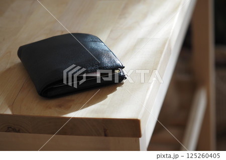 Wallet resting on a wooden table in warm natural light, lost wallet concept Wallet resting on a wooden table in warm natural light, lost wallet concept 125260405