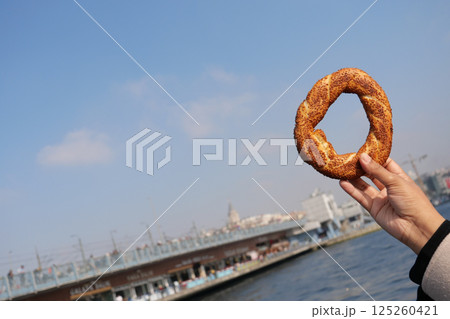 Enjoying a simit by the waterfront in a bustling city 125260421