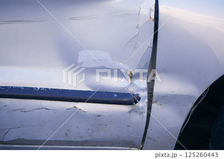 Car damage with visible scratches and dents on the door panel 125260443