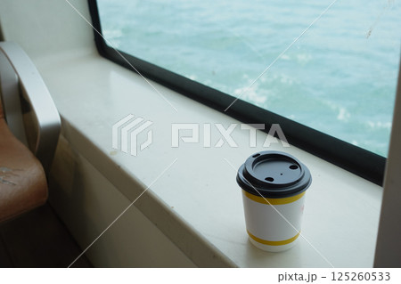 Coffee cup resting on a windowsill with ocean view Coffee cup resting on a windowsill with ocean view 125260533