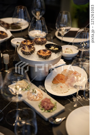 Champagne tasting, Wine glasses are on the table, stylish table setting, wine is poured from a bottle and decanter, sparkling wine bubbles, snacks, people smell the aroma and taste the wine 125261083