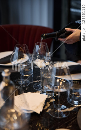 Champagne tasting, Wine glasses are on the table, stylish table setting, wine is poured from a bottle and decanter, sparkling wine bubbles, snacks, people smell the aroma and taste the wine Champagne tasting, Wine glasses are on the table, stylish table setting, wine is poured from a bottle and decanter, sparkling wine bubbles, snacks, people smell the aroma and taste the wine 125261110