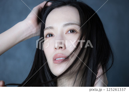 グレーバックで髪がなびく美容やビューティー、決意や意志の強さがカッコイイ真剣な表情の女性 125261337