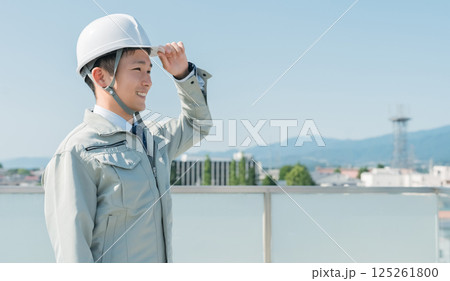 青空の中に立つ作業服を着た作業員（建設・建築・設計・不動産・土木・工事・現場監督・運送） 125261800