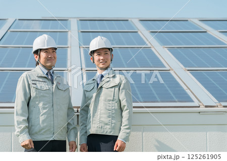 太陽光発電・ソーラーパネルの前に立つ電力会社・電気工事業者の作業着姿の技術者(クリーンエネルギー) 太陽光発電・ソーラーパネルの前に立つ電力会社・電気工事業者の作業着姿の技術者(クリーンエネルギー) 125261905