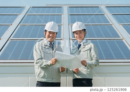 太陽光発電・ソーラーパネルの前に立つ電力会社・電気工事業者の作業着姿の技術者(クリーンエネルギー) 太陽光発電・ソーラーパネルの前に立つ電力会社・電気工事業者の作業着姿の技術者(クリーンエネルギー) 125261906