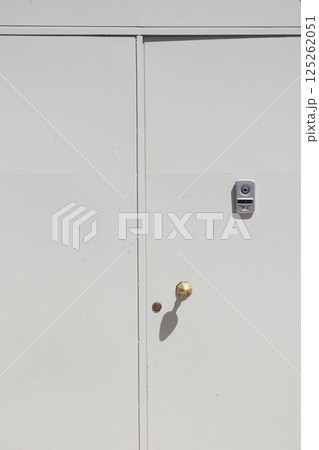 White door with brass doorknob and lock detail captured in daylight 125262051