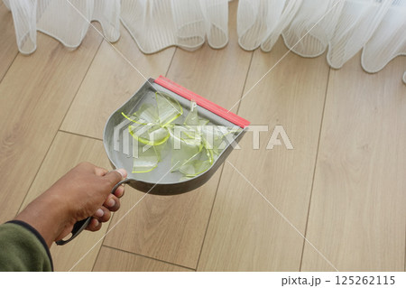 Cleaning up broken glass with a dustpan in a bright room 125262115