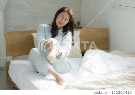 足が攣った寝室のシニア女性　 125263419
