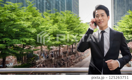 スーツ姿の若い男性が都市の屋外でスマートフォン通話をするポートレート 125263751