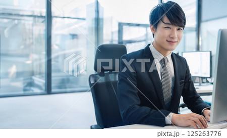 スマートに働く若手ビジネスマンの穏やかな笑顔と洗練されたオフィス風景 125263776