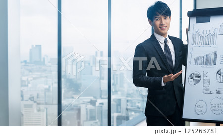 高層オフィスでのプレゼンテーションに臨む若手ビジネスマンの解説シーン 高層オフィスでのプレゼンテーションに臨む若手ビジネスマンの解説シーン 125263781