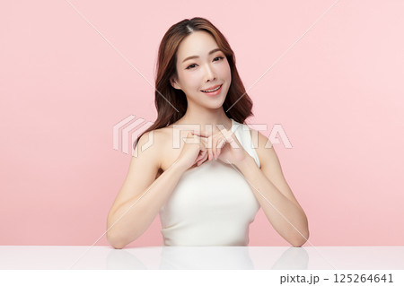 A beautiful young Asian woman with clean, fresh skin against a pink background. Skincare, facial treatment, cosmetology, beauty, and spa. An elegant portrait of an Asian woman. 125264641