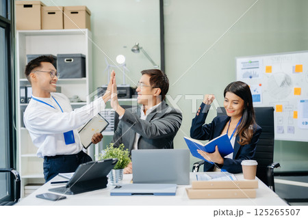Happy Asian businesspeople while collaborating on a new project.  using a laptop and tablet 125265507