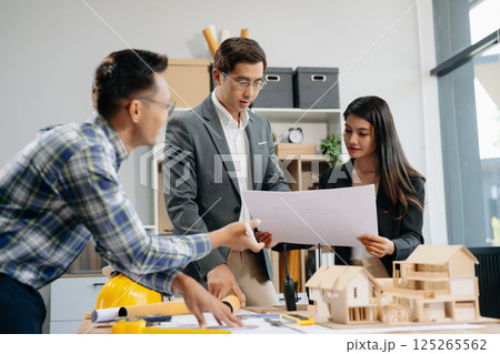 Engineer teams meeting working together wear worker helmets hardhat with on architectural project site and making model house. Asian industry professional team 125265562