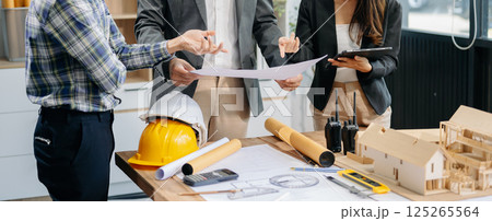 Engineer teams meeting working together wear worker helmets hardhat with on architectural project site and making model house. Asian industry professional team Engineer teams meeting working together wear worker helmets hardhat with on architectural project site and making model house. Asian industry professional team 125265564