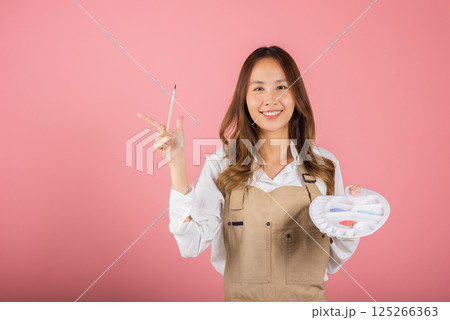 Asian beautiful young woman artist holding brush and paint palette, Happy female painting using paintbrush and palette with colors, studio shot isolated on pink background, Paintings and art equipment Asian beautiful young woman artist holding brush and paint palette, Happy female painting using paintbrush and palette with colors, studio shot isolated on pink background, Paintings and art equipment 125266363