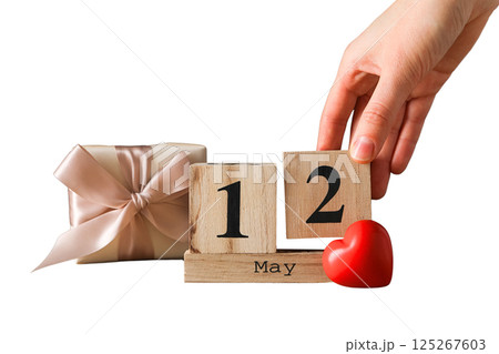 Hand places a wooden block calendar showing May 12, isolated on white 125267603