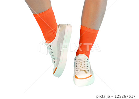 Summer shoes, Feet wearing trendy sneakers and bright orange socks showcase a playful, fashionable look, isolated on white, PNG 125267617