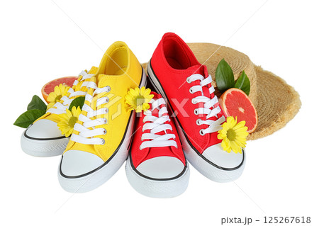Summer shoes, Bright yellow and red sneakers nestle among flowers, leaves, and a straw hat, summoning summer, isolated on white, PNG 125267618