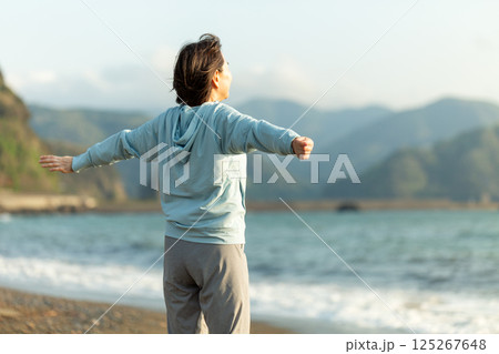夕方の海岸でストレッチ体操をするミドル女性 夕方の海岸でストレッチ体操をするミドル女性 125267648