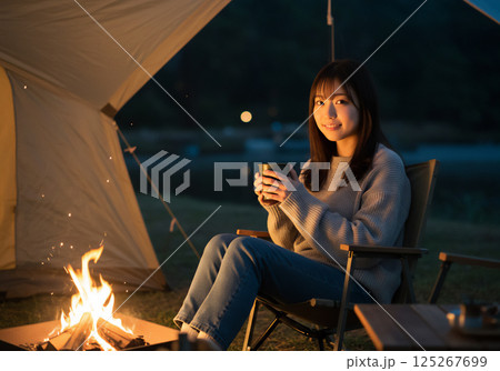 焚き火を囲んで温まる女性 125267699