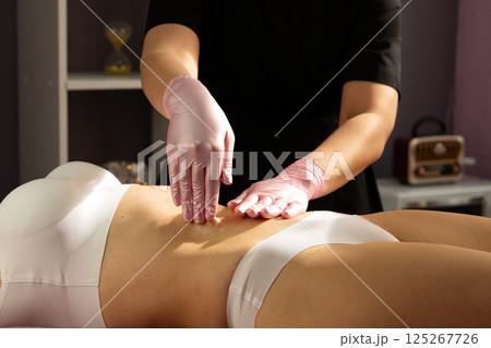 Spa therapist performs abdominal massage with circular hand movements. 125267726