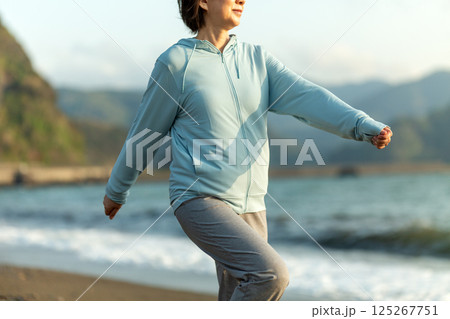 夕方の海岸でウォーキングをするミドル女性 125267751