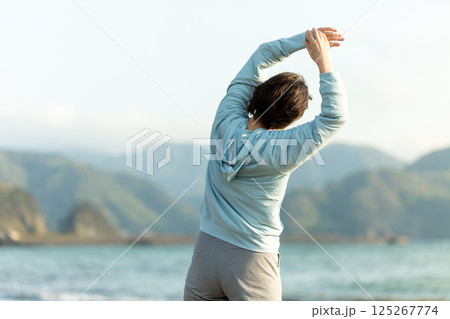 夕方の海岸でストレッチ体操をするミドル女性 125267774