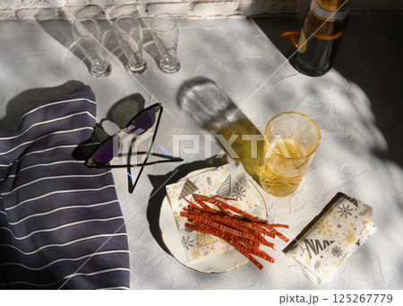 Still life with a glass of beer, fish straws, sunglasses and a vest, casting shadows from the sun 125267779