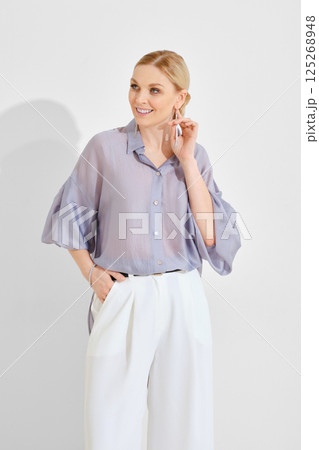 Stylish woman poses in trendy outfit with relaxed elegance in bright indoor setting 125268948