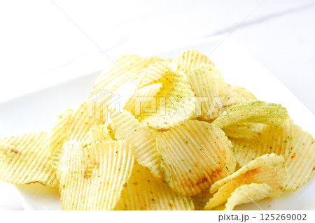 白い皿に山盛りのポテトチップス 125269002