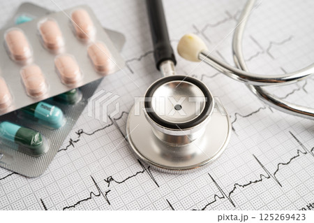 Stethoscope on electrocardiogram ECG with capsule drug, heart wave, heart attack, cardiogram report. 125269423