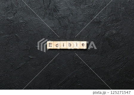 EDIBLE word written on wood block. EDIBLE text on cement table for your desing, concept 125271547