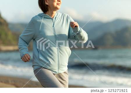 夕方の海岸でランニングをするミドル女性 125271921