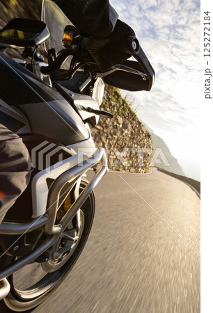 Motorcycle rider riding in Italian Alps during sunrise, dramatic sky. Travel and freedom, outdoor activities Motorcycle rider riding in Italian Alps during sunrise, dramatic sky. Travel and freedom, outdoor activities 125272184