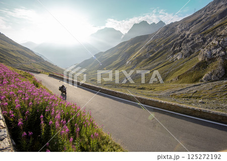 Motorcycle rider riding in Italian Alps during sunrise, dramatic sky. Travel and freedom, outdoor activities Motorcycle rider riding in Italian Alps during sunrise, dramatic sky. Travel and freedom, outdoor activities 125272192