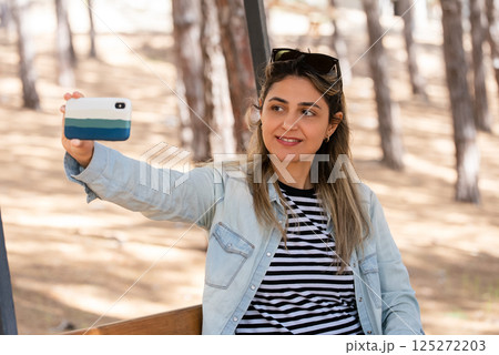 Portrait of smiling woman taking selfie with smartphone 125272203