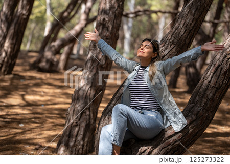 Portrait of a woman with her arms raised in forest. 125273322