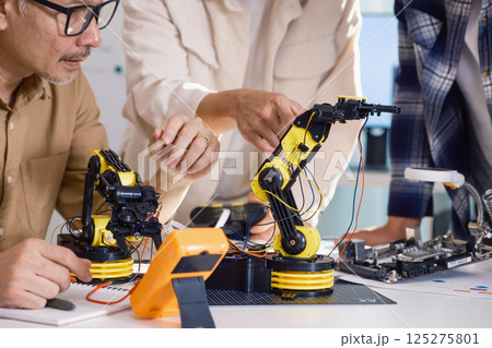 asian Robot arm engineers brainstorming in workshop to develop control technology with teamwork and coding innovation 125275801