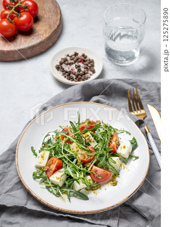 Healthy arugula salad with cherry tomatoes, mozzarella and pesto sauce on a plate Healthy arugula salad with cherry tomatoes, mozzarella and pesto sauce on a plate 125275890