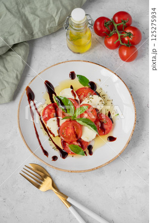 Fresh Caprese salad with sliced tomatoes, mozzarella cheese, basil leaves and balsamic glaze 125275934