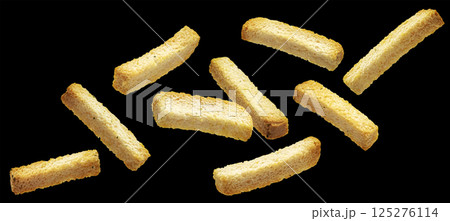 Crispy white bread rusks falling on black background, crunchy snack sticks 125276114