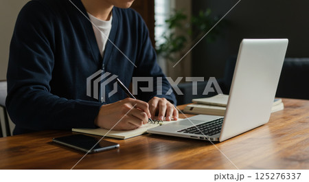 自宅でノートPCで勉強をする男性の手元 125276337