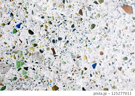 Granite texture with colorful pebbles. Bright glasses on a gray cement background. 125277011